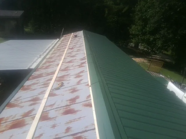 Old rusted panels beside newly installed green metal roofing — Wind Damage Roof Repair by Roofing Brothers in Grabill