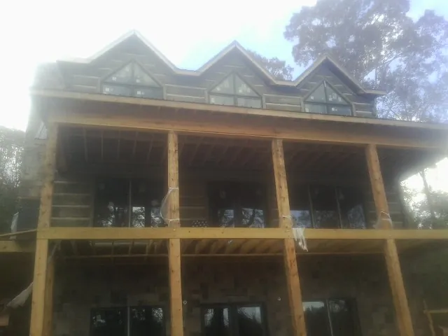 Dormers and porch framing on a large log home under construction — Roof Coating work by our crew in Grabill