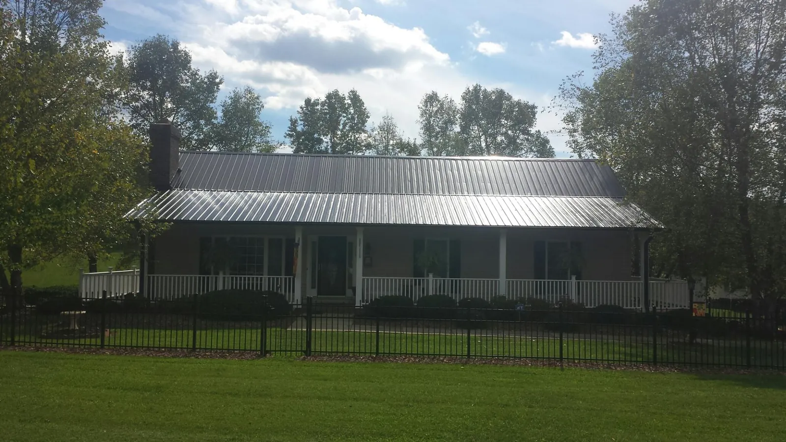 Gray metal roof on a brick ranch with a full width front porch — Gutter Guard Installation work by our crew in Grabill