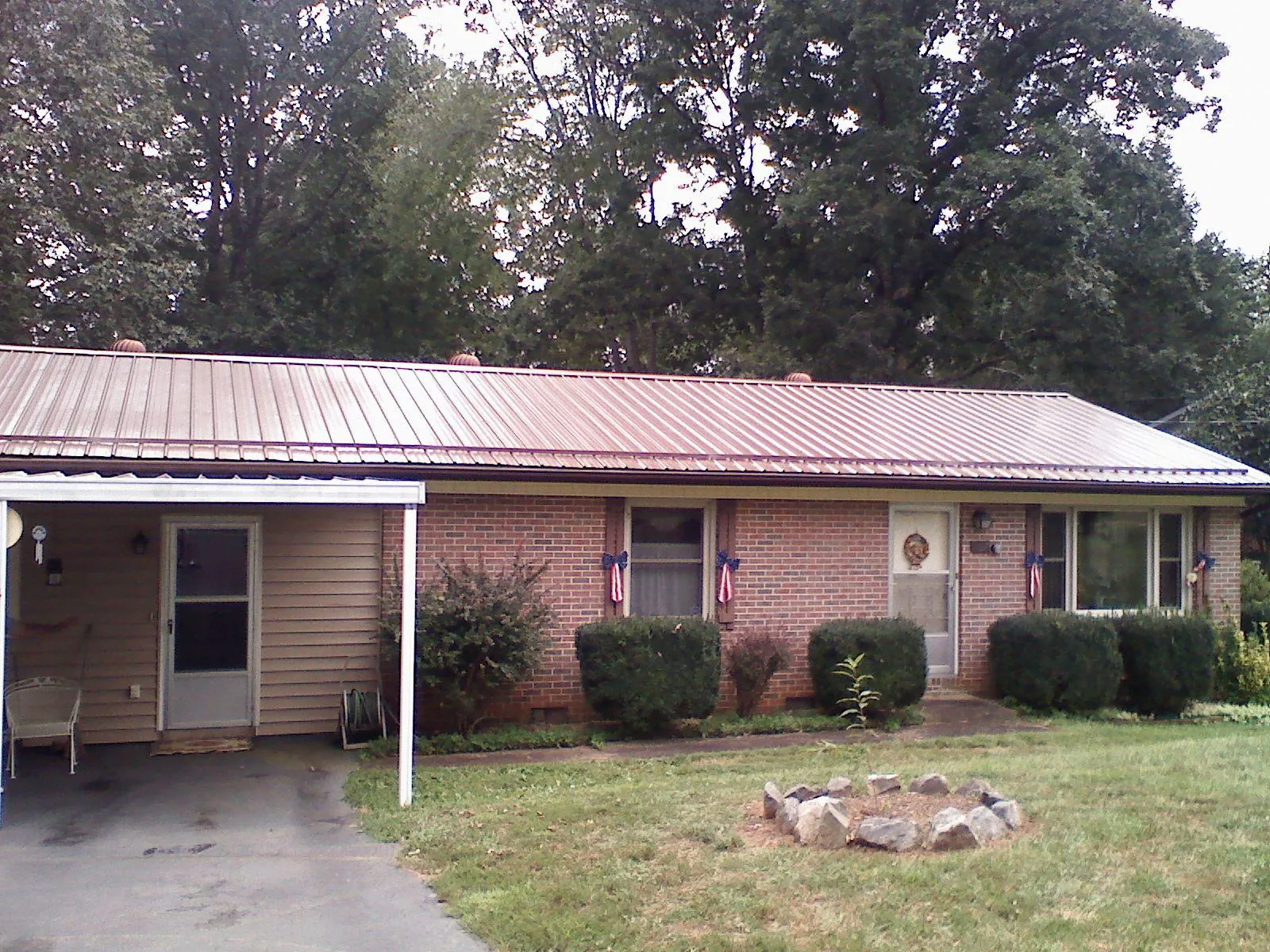 Bronze metal roof and carport on a brick ranch home — Roof Repair work by our crew in Grabill